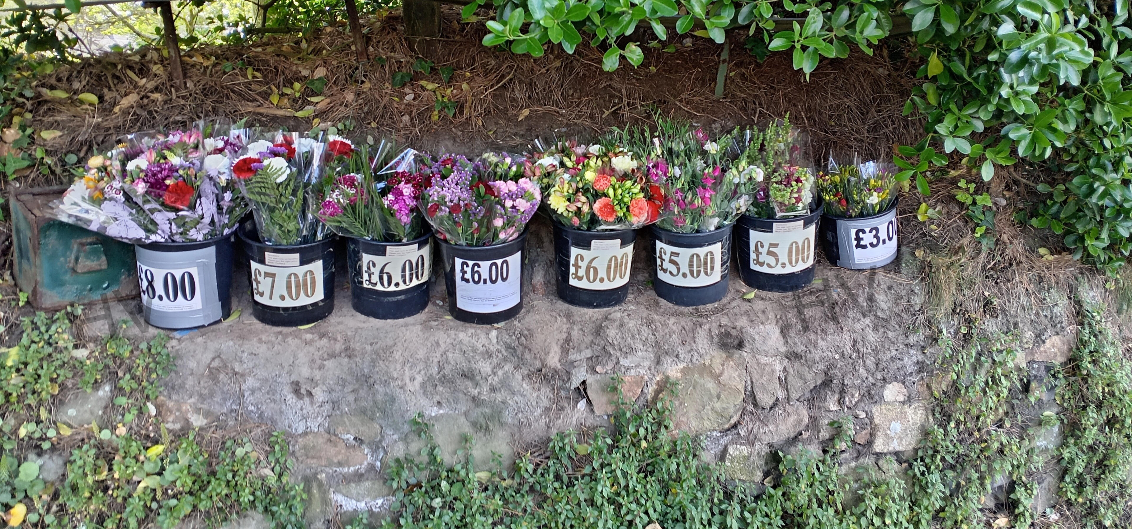 flowers stall set into old stone wall wooden shed surrounded by roses